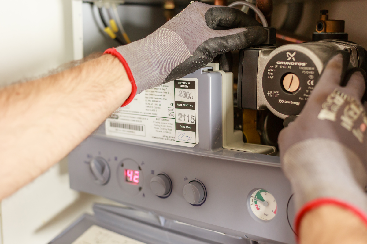 Boiler servicing by J. Annear Plumbing and Heating. Plumbing and heating engineer servicing a boiler, adjusting pump settings and controls.