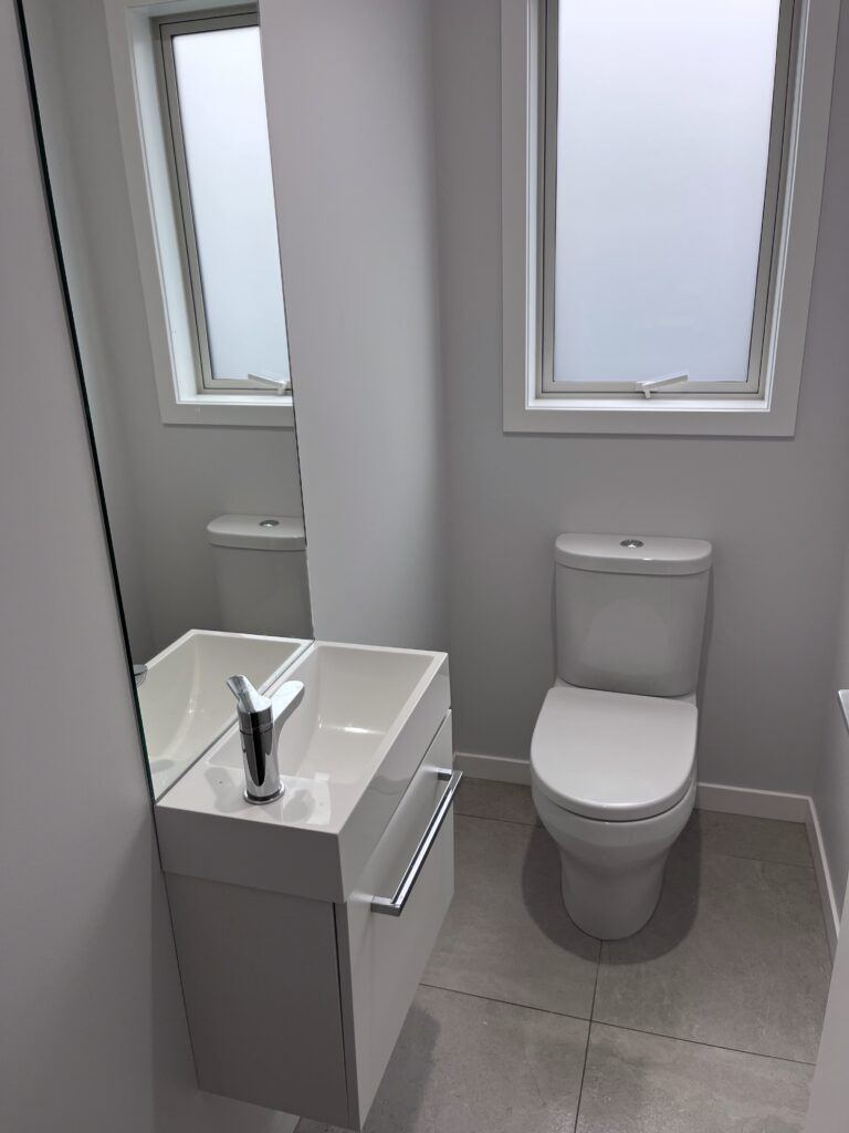 Compact bathroom with fitted toilet and wall-mounted vanity unit, showing professional bathroom installation.