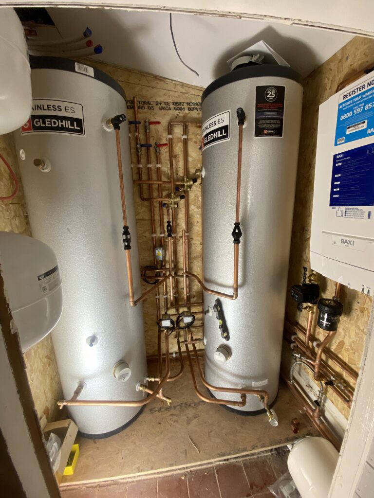 Twin Gledhill hot water cylinders connected with copper pipework in a domestic heating system. Baxi heat only boiler.