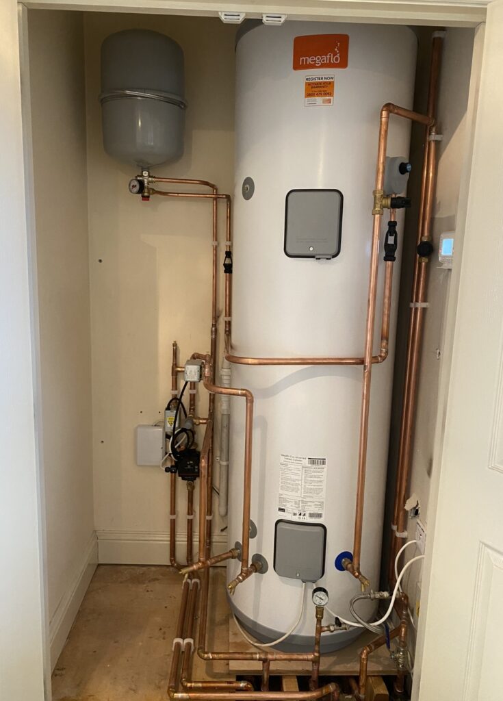 Megaflo hot water cylinder installed with copper pipework in an airing cupboard.