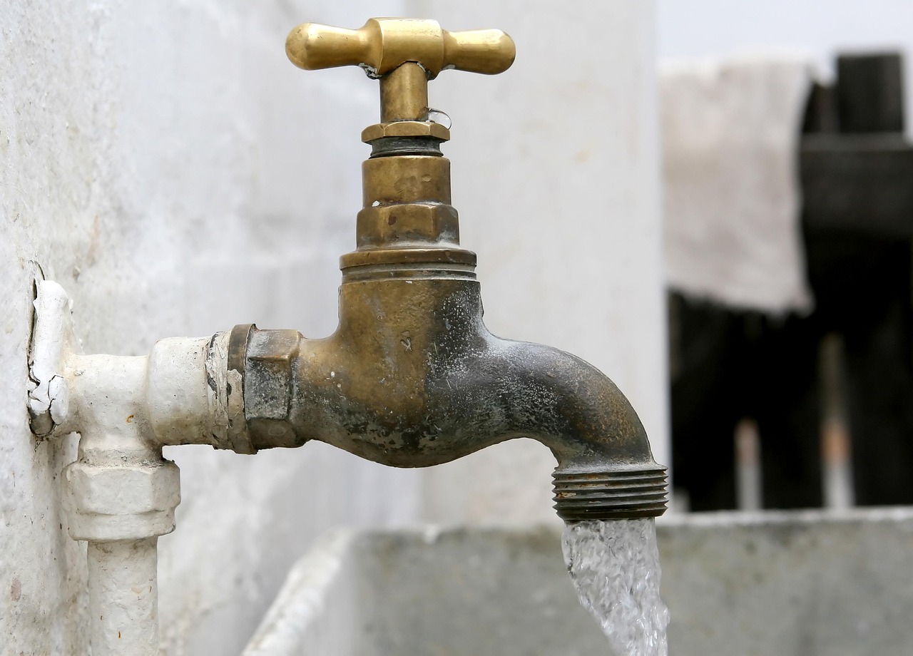 Outdoor brass tap with running water, illustrating plumbing repair and maintenance services.