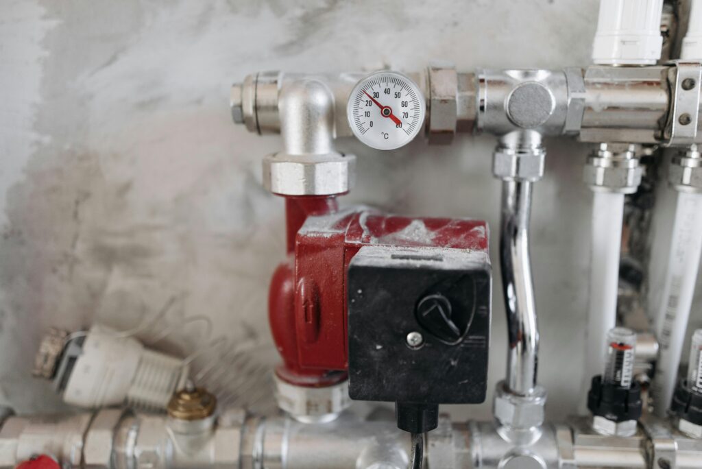 Close-up of central heating pump, pipes and temperature gauge as part of a plumbing and heating system in Gloucestershire.