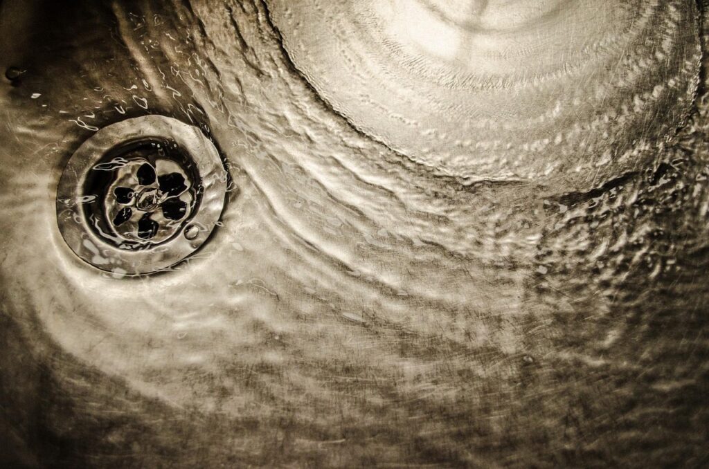 Close-up of water draining through a sink, representing professional plumbing and drainage services.